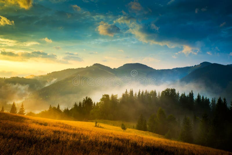 Incredibile paesaggio di montagna con la nebbia e un pagliaio.