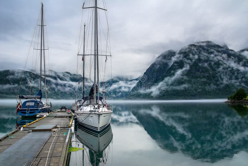 Amazing nature landscape view of lake surrounded by foggy mountains. Sailing vessels or ships. Nature lake. Forest natural.