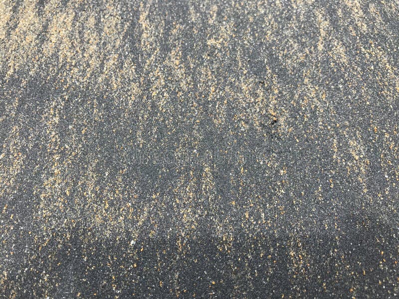 Pattern of Black Wood Charcoal Dust Mixed with Brown Sand on Beach
