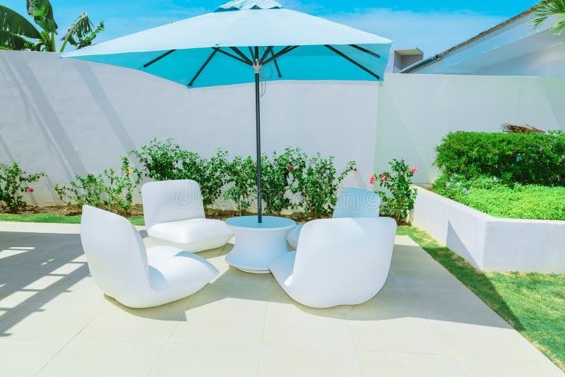 Relaxing inviting view of luxury outdoor backyard furniture with blue great umbrella and comfortable white beautiful chairs