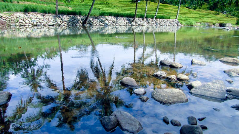 Clear water reflects the shadow of the sky perfectly. River in Tasikmalaya Regency, West Java, Indonesia. Clear water reflects the shadow of the sky perfectly. River in Tasikmalaya Regency, West Java, Indonesia