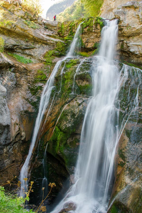 amazing silk effect waterfall in ordesa national park, Spain. A person is enjoying the spectacular view of the cliff and waterfall