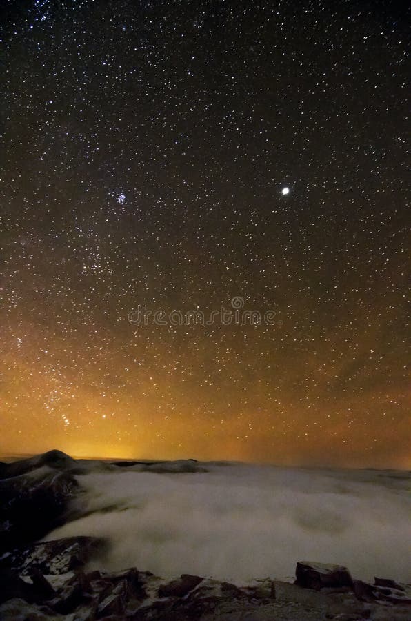 Amazing star night over cloudy mountains