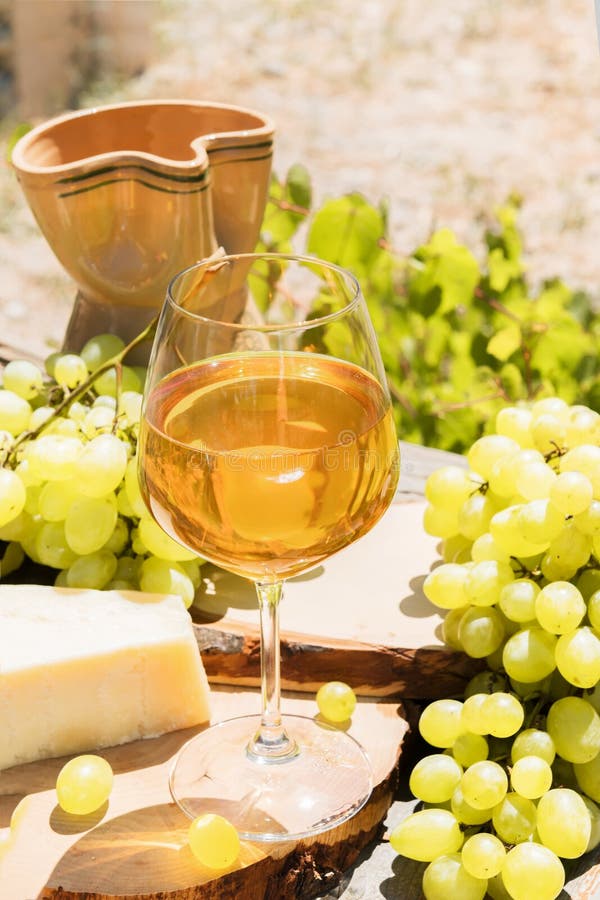 Amber wine in glasses on the nature: still life with cheese, grapes and wine in a rustic style. Georgian national wine or italian. Beautiful still life with stock photos Amber wine in glasses on the nature: still life with cheese, grapes and wine in a rustic style. Georgian national wine or italian. Beautiful still life with stock photos