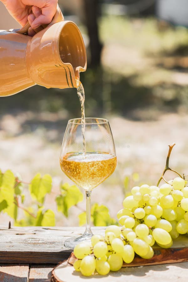 Amber wine in glasses on the nature: still life with cheese, grapes and wine in a rustic style. Georgian national wine or italian. Amber wine puoring in the stock image Amber wine in glasses on the nature: still life with cheese, grapes and wine in a rustic style. Georgian national wine or italian. Amber wine puoring in the stock image