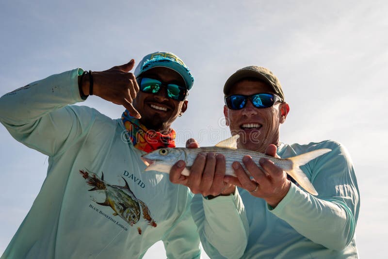 Happy fly fisherman with Belizean guide shows off the bonefish he caught