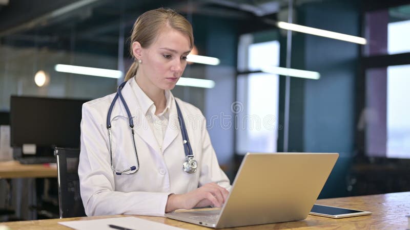 Ambiciosa joven médica trabajando en una laptop en el consultorio