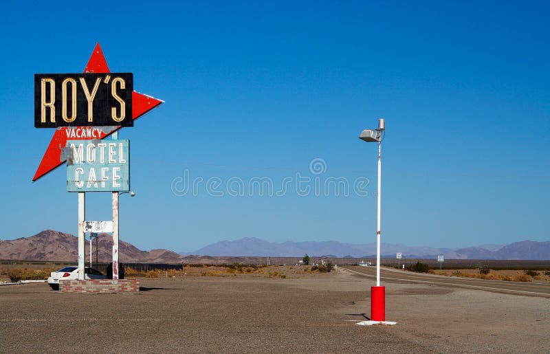 AMBOY KALIFORNIEN, USA - AUGUSTI 8 2009: Isolerat tecken av Roys motell och kafé mot blå himmel på Route 66 med bergskedja royaltyfria foton AMBOY KALIFORNIEN, USA - AUGUSTI 8 2009: Isolerat tecken av Roys motell och kafé mot blå himmel på Route 66 med bergskedja royaltyfria foton