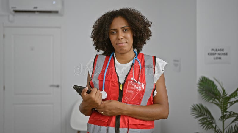 Ambulancière noire avec stéthoscope dans le couloir de la clinique photographie stock libre de droits
