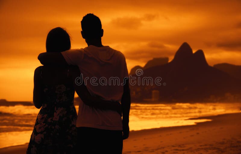 Ame pares nos braços na praia no por do sol em Rio de janeiro