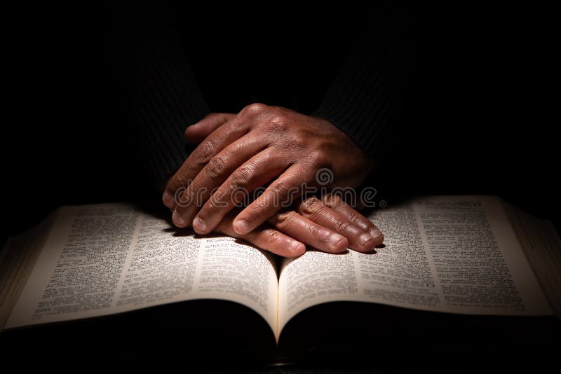 American african care se roagă cu mâinile pe Biblie stock photography
