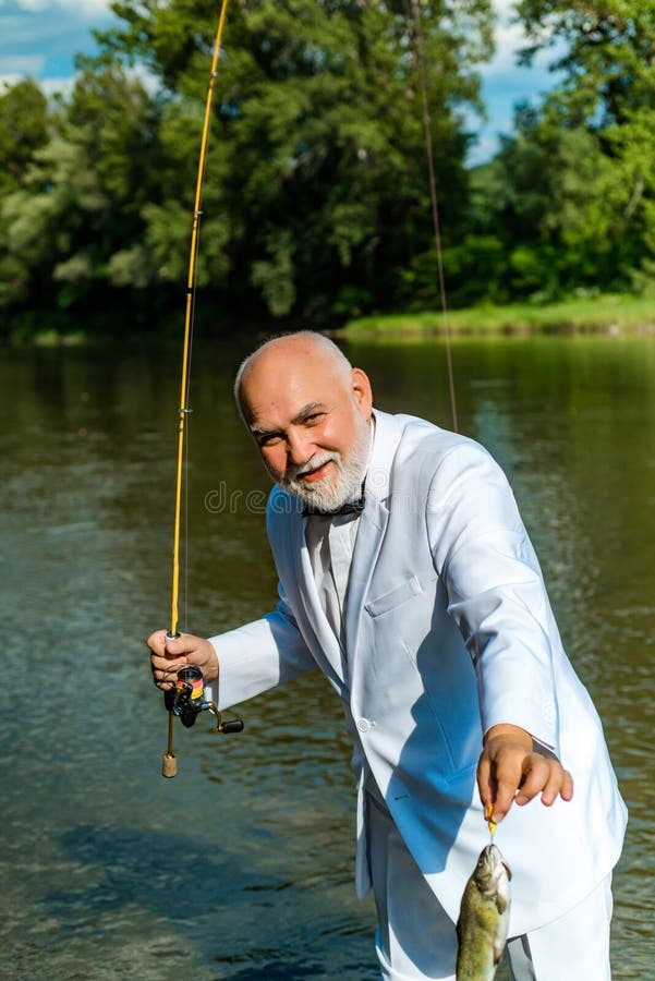 American angler fishing. Still water trout fishing. Handsome mature fisherman in white suit fishing in a river with a