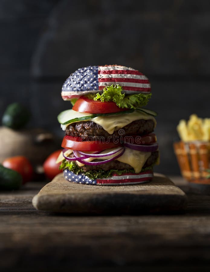 American Burger with tomatoes, onions, cucumber, lettuce and melting cheese. United States of America flag. Happy independence day