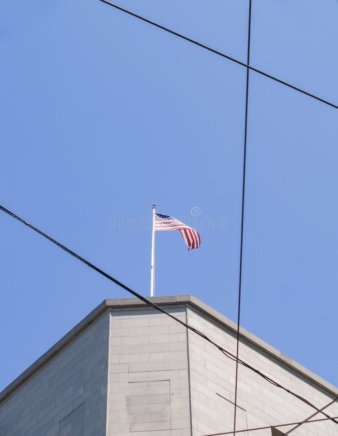 American Flag Atop Building Against Blue Sky Crossed by Power-lines ...