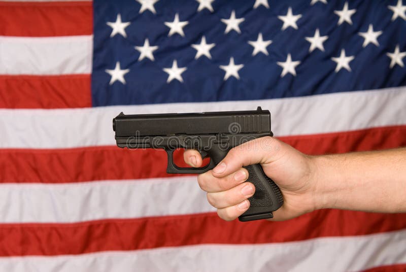 A man displays his semi automatic pistol against an American flag. A man displays his semi automatic pistol against an American flag.