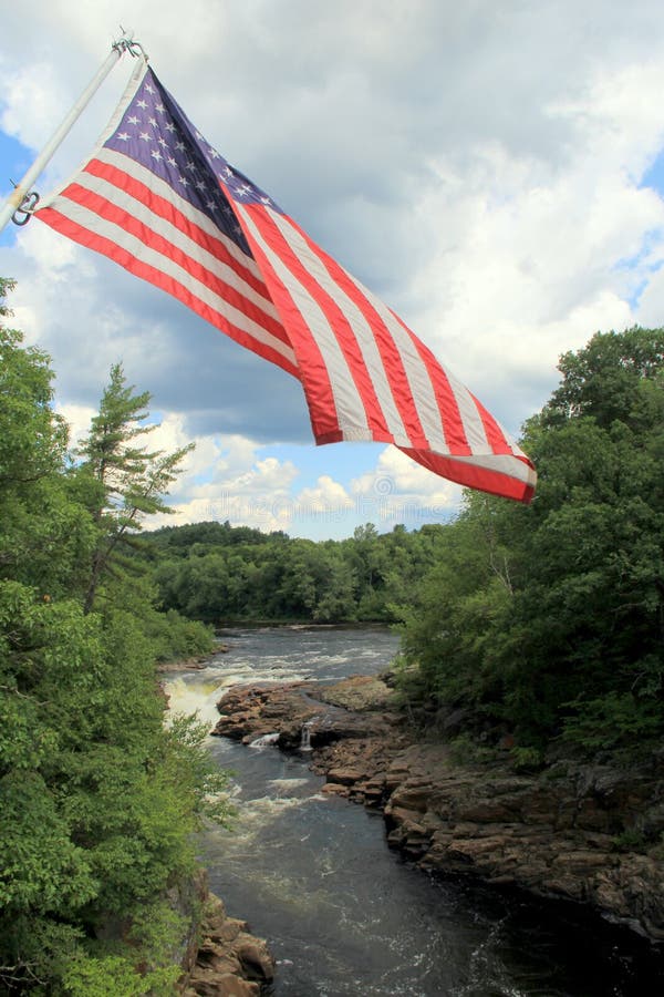 American flag waving over raging waters of river