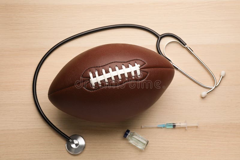 American football ball, stethoscope and drugs on wooden table, flat lay. Doping concept