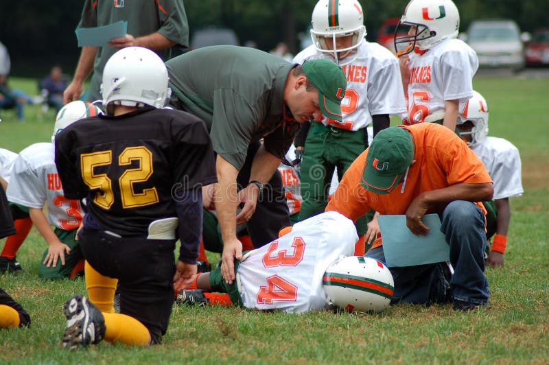 This is a photograph of an injured child in a football game. He is being cared for by the coaches. This is a photograph of an injured child in a football game. He is being cared for by the coaches.
