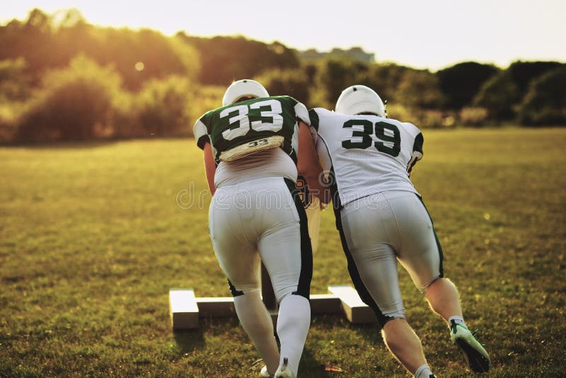 American football players pushing a tackling slide on a field