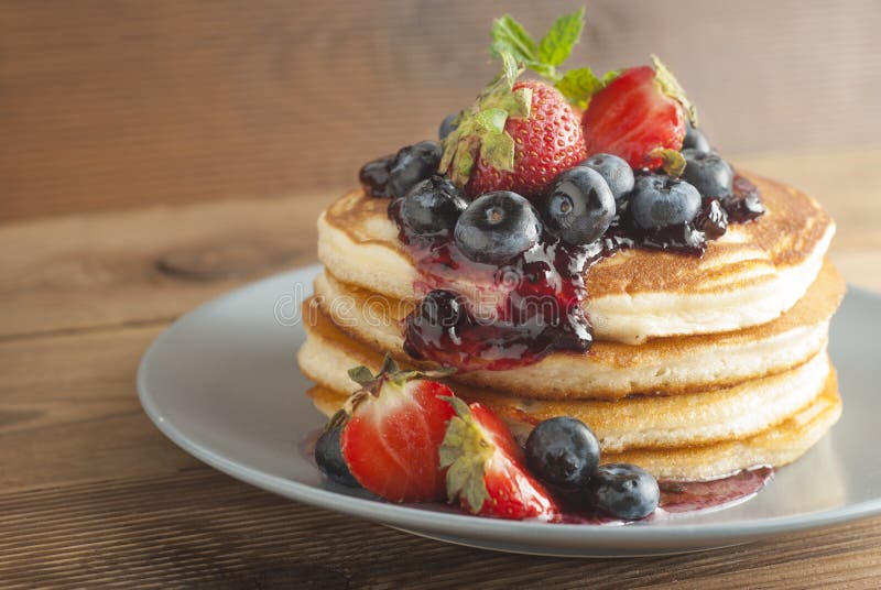 American pancakes or fritters served with strawberry and blueberry jam, delicious dessert for breakfast, rustic style, wooden back stock photo American pancakes or fritters served with strawberry and blueberry jam, delicious dessert for breakfast, rustic style, wooden back stock photo