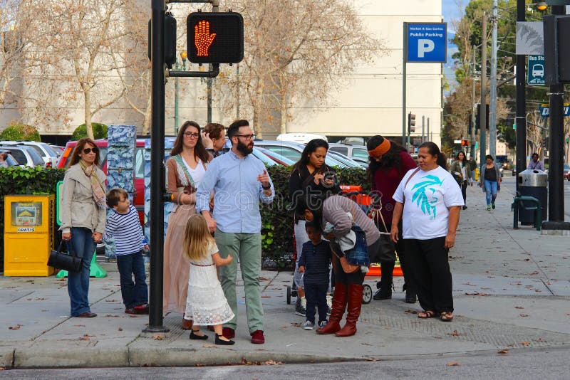 San Jose, California, United States - December 06, 2014: Several American families with children staying at the crosswalk and wait for the signal allowing traffic. Behind them a parking and a building. San Jose, California, United States - December 06, 2014: Several American families with children staying at the crosswalk and wait for the signal allowing traffic. Behind them a parking and a building.