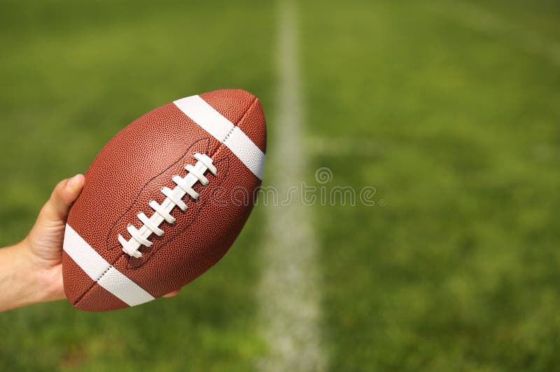 Amerikanischer Fußball in der Hand lizenzfreie stockbilder Amerikanischer Fußball in der Hand lizenzfreie stockbilder