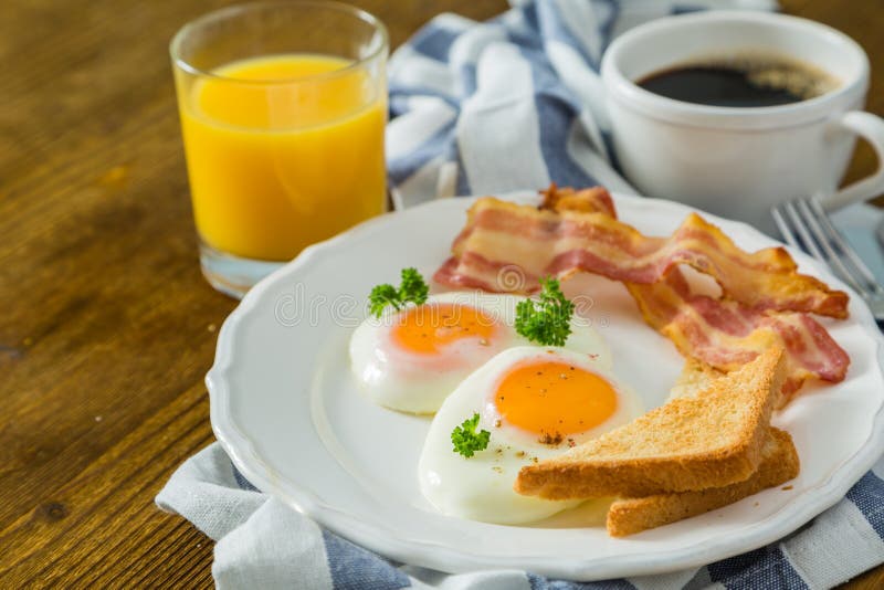 Amerikanisches Frühstück mit Sonnenseite herauf Eier, Speck, Toast, Pfannkuchen, Kaffee und Saft lizenzfreie stockfotos Amerikanisches Frühstück mit Sonnenseite herauf Eier, Speck, Toast, Pfannkuchen, Kaffee und Saft lizenzfreie stockfotos