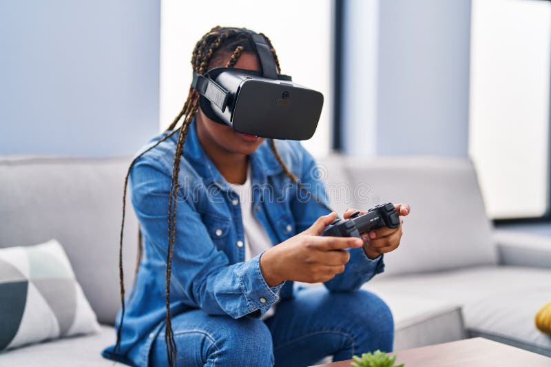 Amerikanska kvinnor spelar videospel med hjälp av virtuella verklighetsglasögon och joystick hemma royaltyfri bild