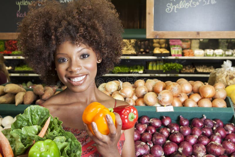 African American women holding bell peppers and vegetables at supermarket. African American women holding bell peppers and vegetables at supermarket