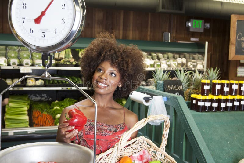 African American women weighing bell peppers on scale at supermarket. African American women weighing bell peppers on scale at supermarket