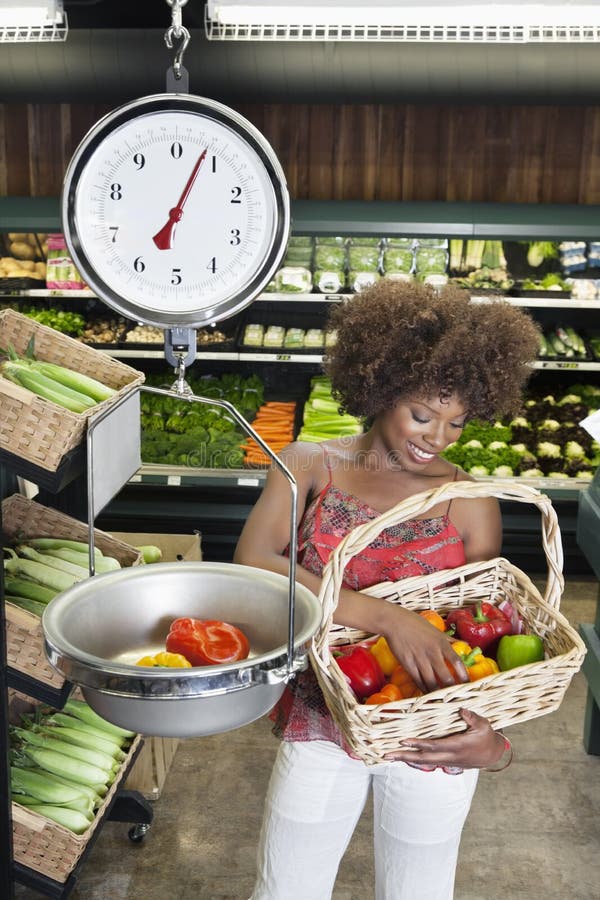 African American women weighing bell peppers on scale at supermarket. African American women weighing bell peppers on scale at supermarket