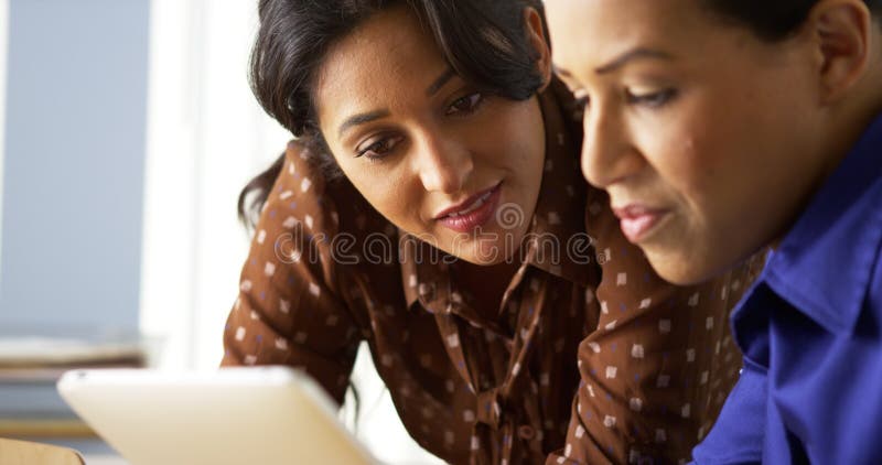 African American and Hispanic business women using tablet computer. African American and Hispanic business women using tablet computer