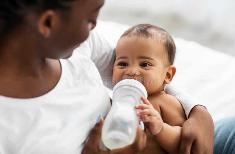 Amerykanka afrykańska karmi dziecko butelką dla dzieci