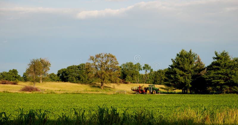 This is a photo of a farmer on a tractor and some of the property around it. This is a photo of a farmer on a tractor and some of the property around it.