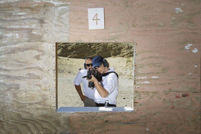 Ametralladora de With Woman Aiming del instructor en la gama de leña fotografía de archivo Ametralladora de With Woman Aiming del instructor en la gama de leña fotografía de archivo