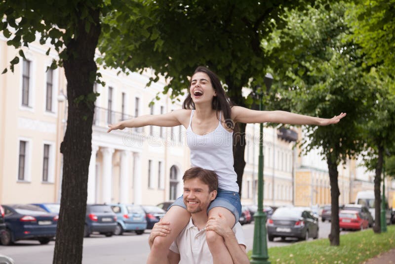 Amica di risata felice che si siede sulle spalle del ragazzo all'aperto immagini stock libere da diritti Amica di risata felice che si siede sulle spalle del ragazzo all'aperto immagini stock libere da diritti