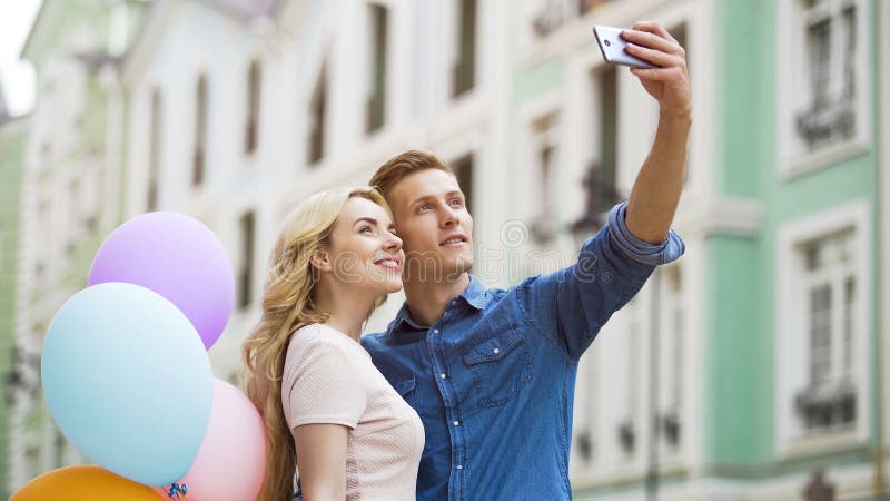 Amica e ragazzo che abbracciano in via e che prendono selfie, foto romantiche immagini stock libere da diritti Amica e ragazzo che abbracciano in via e che prendono selfie, foto romantiche immagini stock libere da diritti