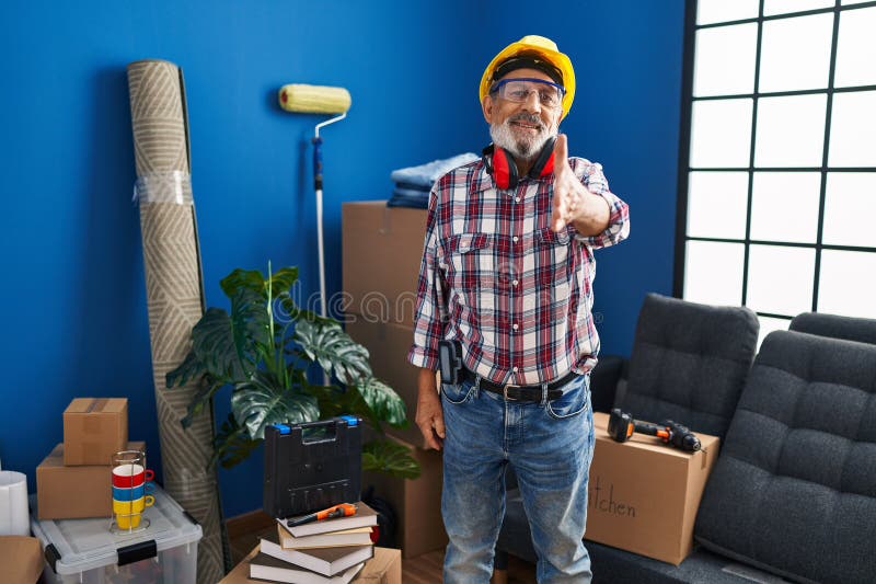 Amical senior man in hardhat et lunettes de sécurité heureux offrir une poignée de main réussie pour le succès des affaires à nouv photo stock