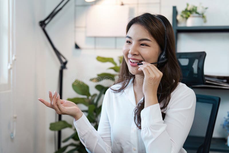 Amichevole agente di call center femminile che fornisce assistenza ai clienti in un ambiente moderno con cuffie e microfono fotografia stock