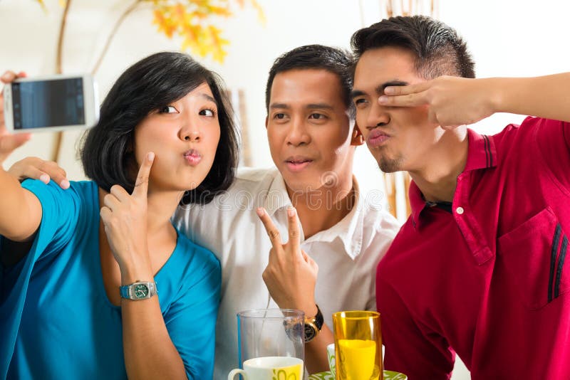 Amici asiatici che catturano le maschere con il telefono cellulare immagini stock libere da diritti Amici asiatici che catturano le maschere con il telefono cellulare immagini stock libere da diritti