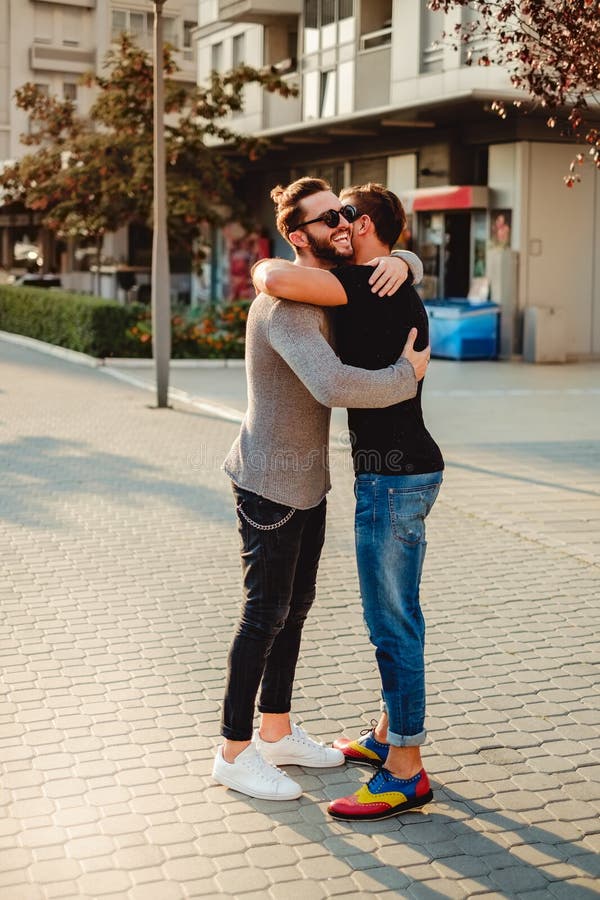 Amici che abbracciano nella via e nel sorridere fotografie stock Amici che abbracciano nella via e nel sorridere fotografie stock
