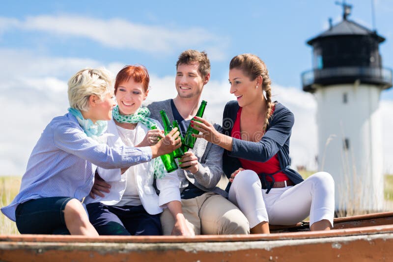 Amici che bevono birra in bottiglia alla spiaggia fotografia stock libera da diritti Amici che bevono birra in bottiglia alla spiaggia fotografia stock libera da diritti