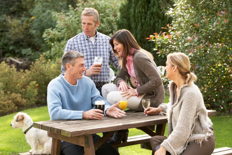 Amici che godono della bevanda nel giardino del Pub immagine stock Amici che godono della bevanda nel giardino del Pub immagine stock