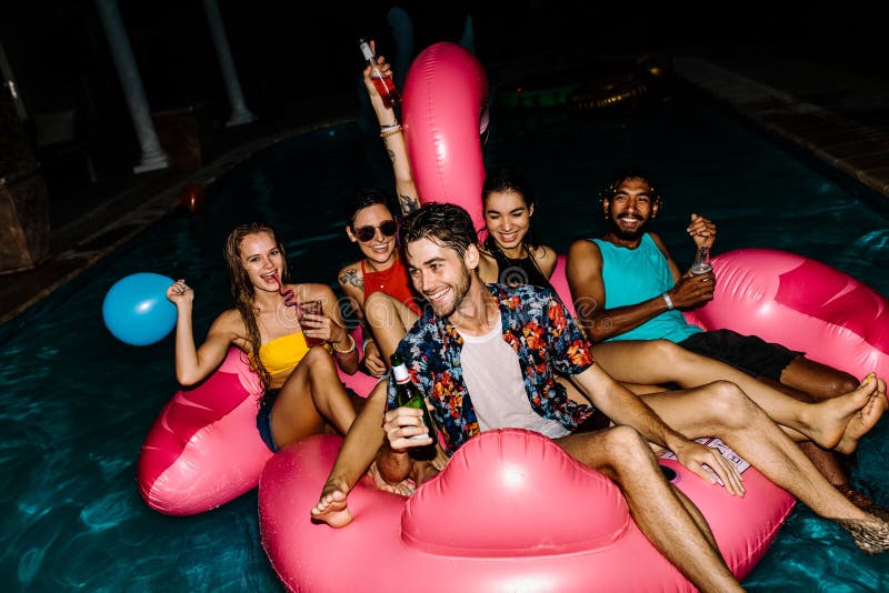 Amici che hanno festa in piscina di sera fotografie stock Amici che hanno festa in piscina di sera fotografie stock