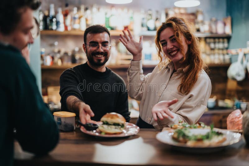 Amici che mangiano insieme in un bar accogliente e vibrante immagini stock