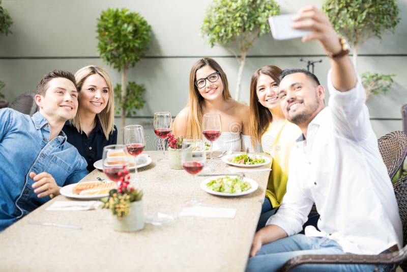 Amici che prendono selfie in un ristorante immagine stock libera da diritti Amici che prendono selfie in un ristorante immagine stock libera da diritti