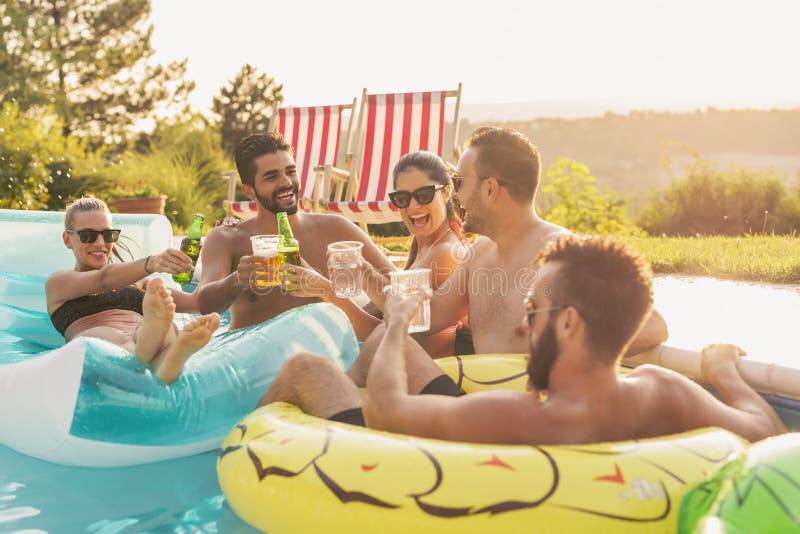 Amici che producono un pane tostato ad un partito del poolside immagine stock libera da diritti Amici che producono un pane tostato ad un partito del poolside immagine stock libera da diritti