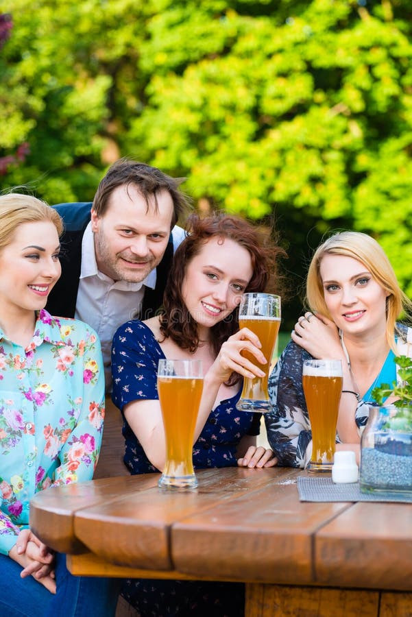 Amici che si siedono nel ristorante del giardino della birra immagini stock Amici che si siedono nel ristorante del giardino della birra immagini stock