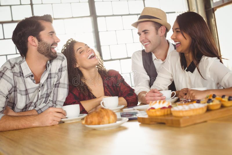 Amici di risata che godono del caffè e degli ossequi fotografia stock Amici di risata che godono del caffè e degli ossequi fotografia stock