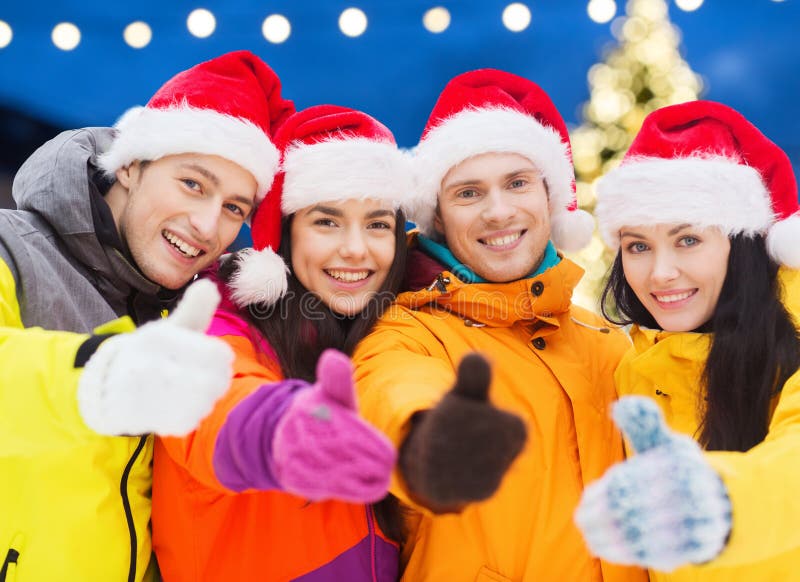 Amici felici in cappelli di Santa e vestiti di sci all'aperto immagini stock libere da diritti Amici felici in cappelli di Santa e vestiti di sci all'aperto immagini stock libere da diritti